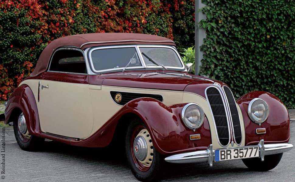 eine EMW 327-5 Cabrio in den Farben beige-bordeaux vor einer grünen Hecke